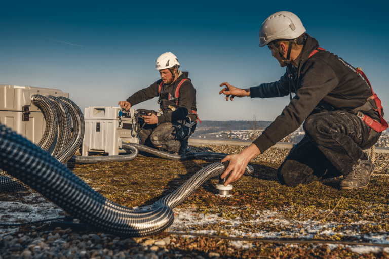 Bild mit zwei Männern, welche ein Flachdach prüfen